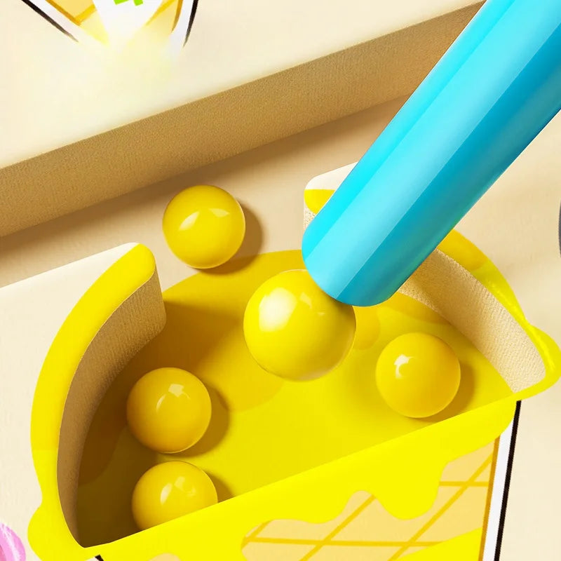 Yellow toy with green balls and a blue handle on a beige surface