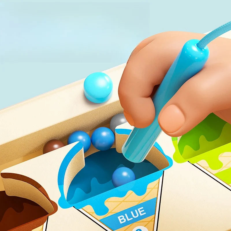 Hand using a blue scoop to pour blue balls into a container labeled 'Blue' on a colorful background.
